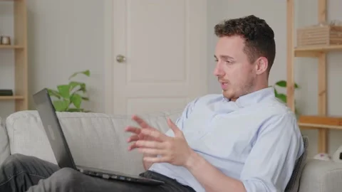 Guy sit on comfy sofa leaned on cushion put laptop on laps talk by video Stock Footage 169017618