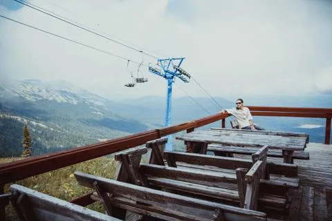 The guy sits on the background of the mountains on a bench Photos