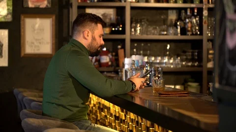 Guy sits at bar counter with glasses of alcohol. Stock Footage 126030588