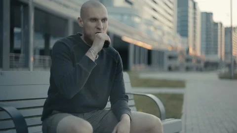 The guy sits on a bench and vaping in the evening on the street Stock Footage 85599648