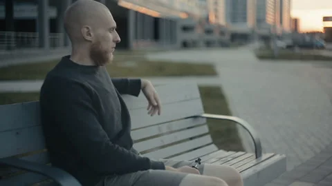 The guy sits on a bench and vaping in the evening on the street Stockbeeldmateriaal 85599653