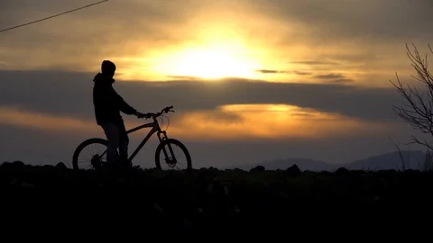 The guy sits on a bicycle, an incredible sunset Stock Footage 122237295