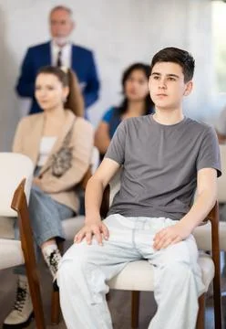 Guy sits in the classroom against the background of other students and listens Stock Photos