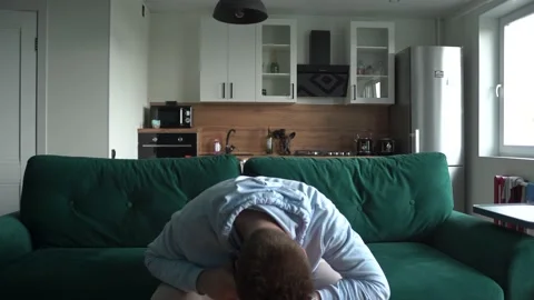 The guy sits on the couch in different positions, tired, bored and waiting Stock Footage 154646686