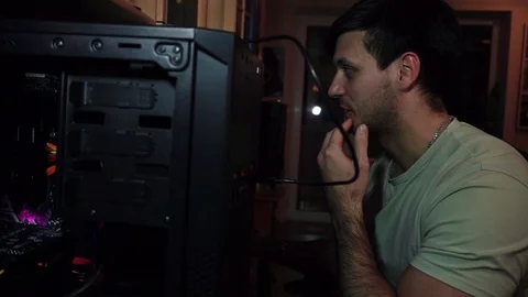 The guy sits at a disassembled computer, talks, smokes an electronic cigarette Stock Footage 121478102