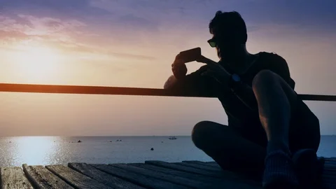 Guy sits on the dock and looks into the smartphone in timelapse Stock Footage 94500563