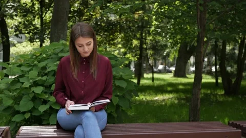 A guy sits down on a bench to a girl with a book Stock Footage 134253093