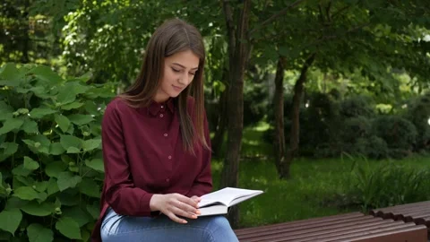 A guy sits down on a bench to a girl with a book Stock Footage 134254274