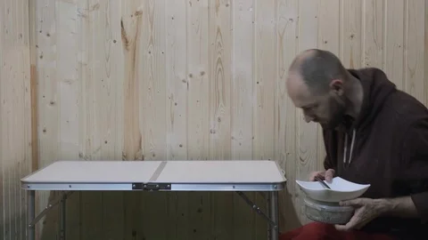 The guy sits down at the table and puts plates of food in front of him Stock Footage 119700232