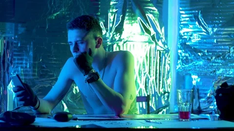 The guy sits down at the table and looks thoughtfully at the phone Vidéo 123573459