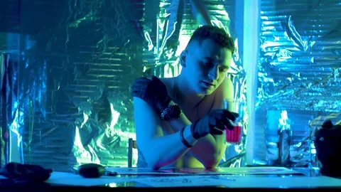 The guy sits down at the table and holds a glass of juice in his hand, shaking i Vidéo 123573499