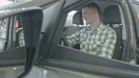 The guy sits on the driver's seat. Happy young self-confident man on the light Stock Footage 101104004