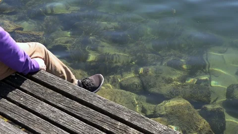 The guy sits on the edge of the pier and shakes his leg Stock Footage 125955117