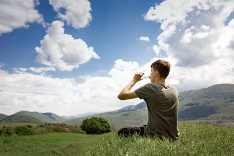 The guy sits on a mountain and drinks water from a bottle. mountain landscape. Stock Photos