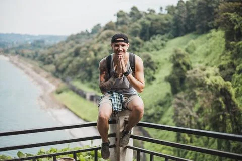 Guy sits on the railing at the observation deck in the jungle. Stock Photos