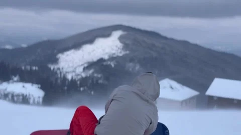 A guy sits on a snowy mountain and looks at the mountains close-up 스톡 동영상 295637310