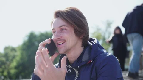 Guy sits on the steps and emotionally communicates on the phone in blue jacket Stock-Footage 163336327