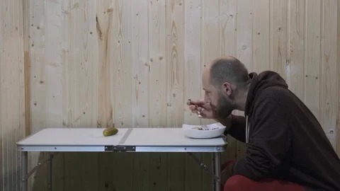 The guy sits at the table and eats porridge with cucumber Stock Footage 119702207