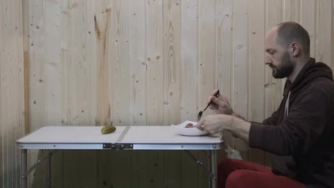 The guy sits at the table and eats porridge from a plate Stock Footage 119704651