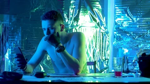 The guy sits at the table and looks thoughtfully at the phone. Vidéo 123573300