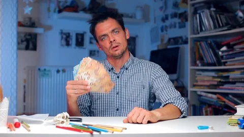 The guy sits at a table in the office, waves a fan of money. COVID 19 Video stock 117279741