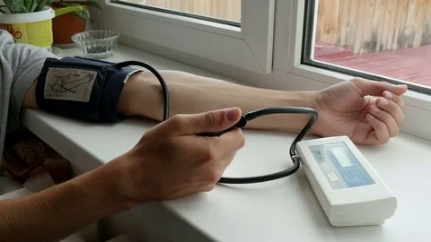 Guy sits at the window and measures the pressure Video stock 80358246