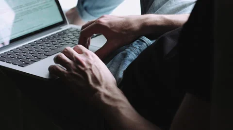 Guy sits on the windowsill and running on the laptop on his lap. Vídeo Stock 68409178