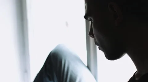 Guy sits on the windowsill and running on the laptop on his lap. Stock Footage 68409392
