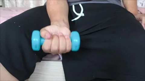 The guy is sitting and lifting dumbbells. an active lifestyle. Stock Footage 313179086