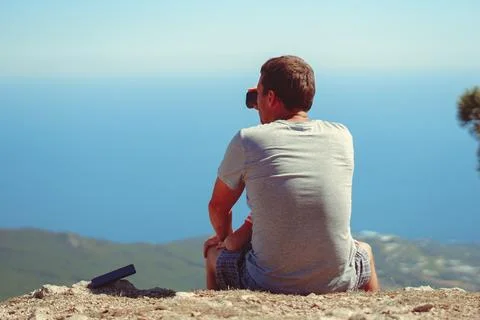 The guy is sitting and looking through binoculars Stock Photos