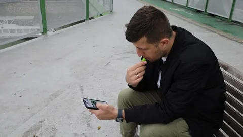 The guy is sitting on a bench and using the phone. Depression. Stock Footage 220227235