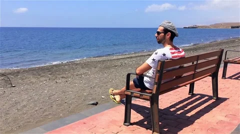 Guy sitting bench beach Stock-Footage 50592836