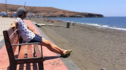 Guy sitting bench beach seafront 動画素材 50592696