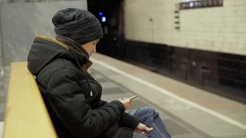 The guy is sitting on a bench in the metro putting his foot on his leg. A Stock Footage 82463068
