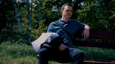 The guy is sitting on a bench overlooking the forest and mountains Stock Footage 107846732