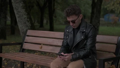 The guy is sitting on a bench in the park 库存影片 219229578