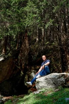 A guy is sitting on a big rock in an Austrian forest Foto stock
