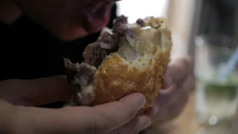 The guy is sitting in a cafe and eating a burger. Burger in hand and bite Stock Footage 109263446