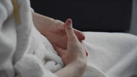 The guy is sitting on a chair in a bathrobe with his palms folded on his knees Stock Footage 250484028