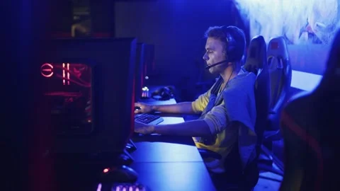 Guy is sitting in a computer club, playing an online game. Company of young Stock Footage 136392473