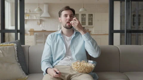 Guy Sitting on Couch and Eating Popcorn Stock Footage 294325900
