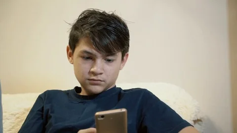 A guy sitting on the couch reading sms on a smartphone. Stock Footage 82488467