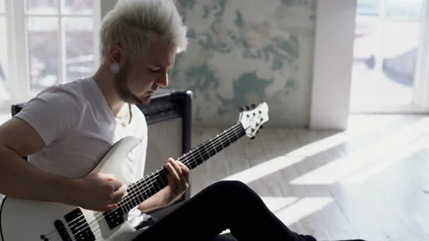 Guy is sitting on the floor and playing the guitar Stock Footage 103998198