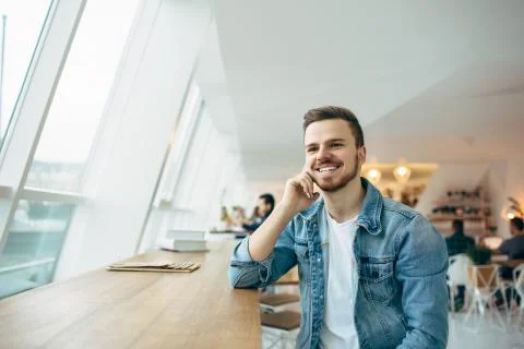 Guy is sitting in front of the table near window Stock Photos