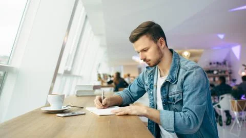 Guy is sitting in front of the table near window Stock Photos