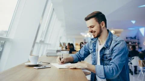 Guy is sitting in front of the table near window Stock Photos