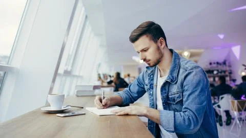 Guy is sitting in front of the table near window Stock Photos