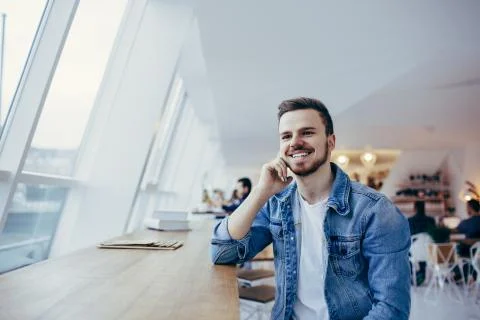 Guy is sitting in front of the table near window Stock Photos