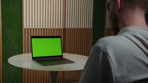 The guy sitting with his back looking at the laptop monitor with chroma key Stock Footage 194162686