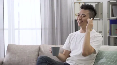 Guy sitting on living room sofa and chatting Stock Footage 140149488